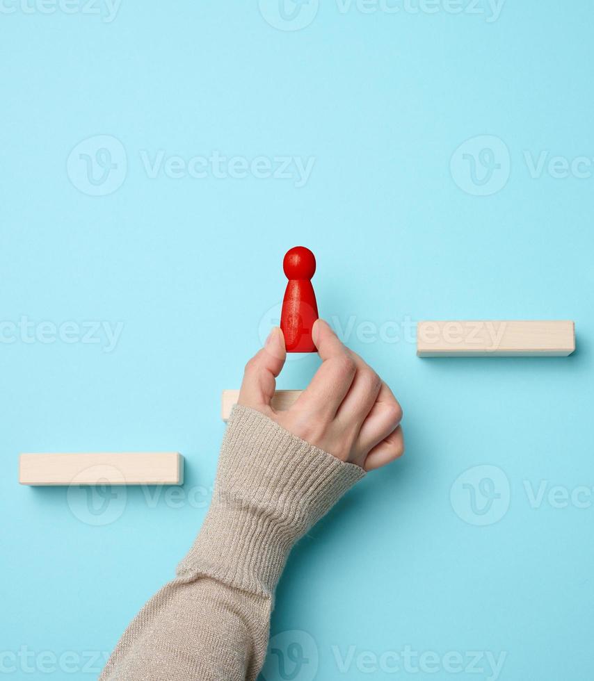 Wooden steps and a figurine of a little man in a woman's hand. Startup, starting a new successful business, achieving goals photo