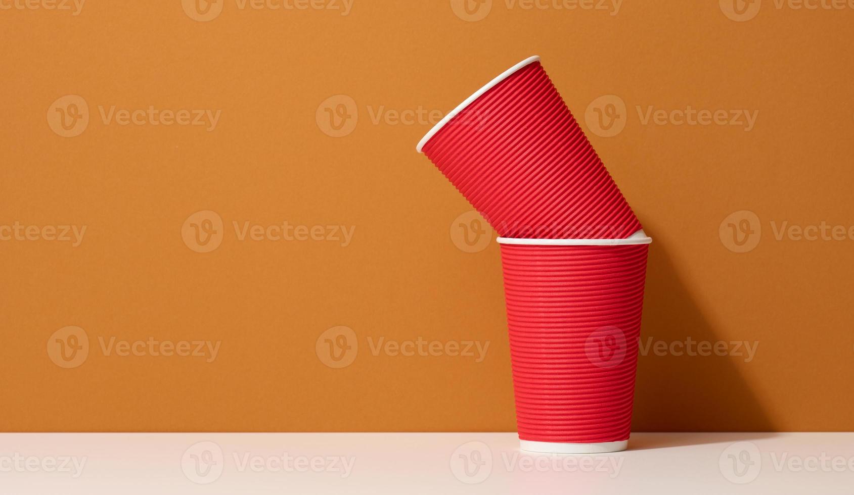 paper cardboard red cups for coffee, orange background. Eco-friendly tableware photo