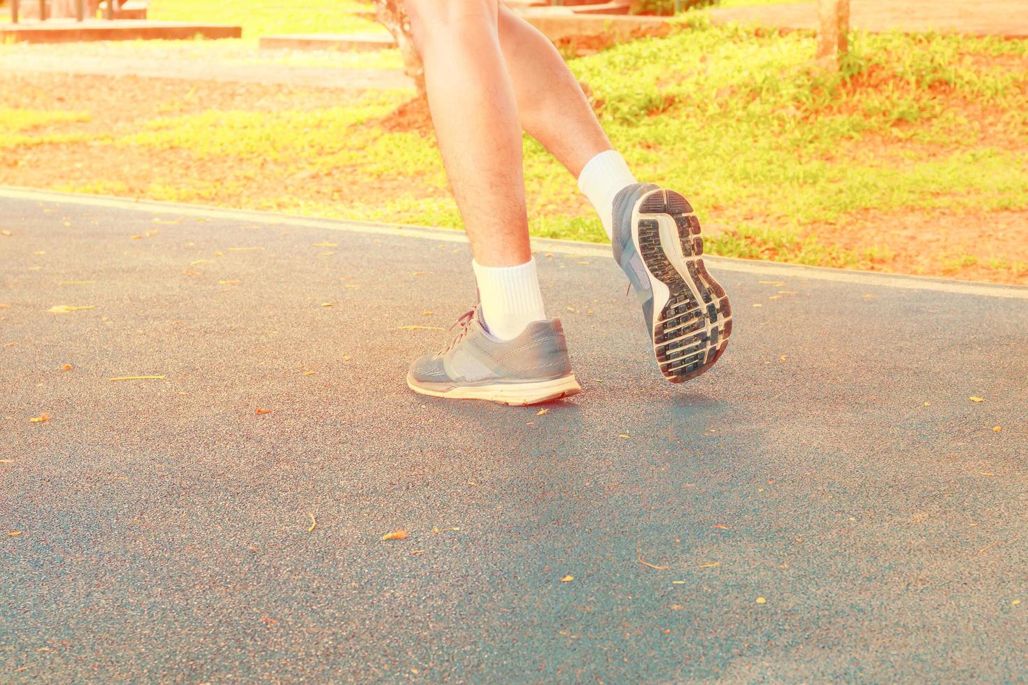 running feet male in runner jogging exercise with old shoes for health lose weight concept on track rubber cover blue public park. copy space add text. Vintage toning. photo