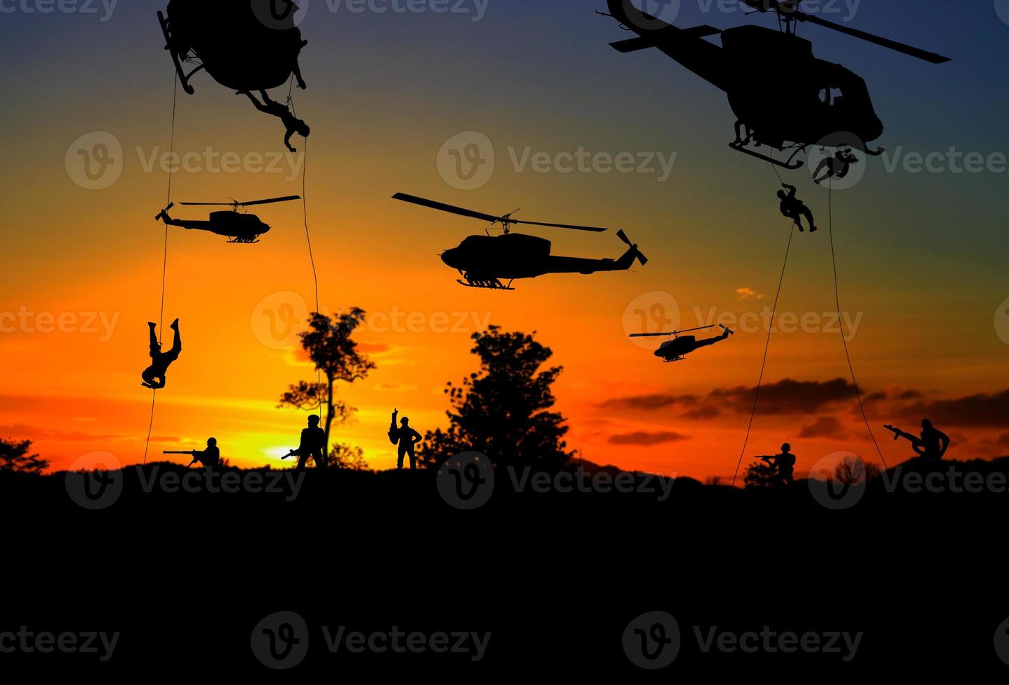 Silhouette Soldiers rappel down to attack from helicopter with warrior beware danger On the ground sunset Background blur and copy space add text photo