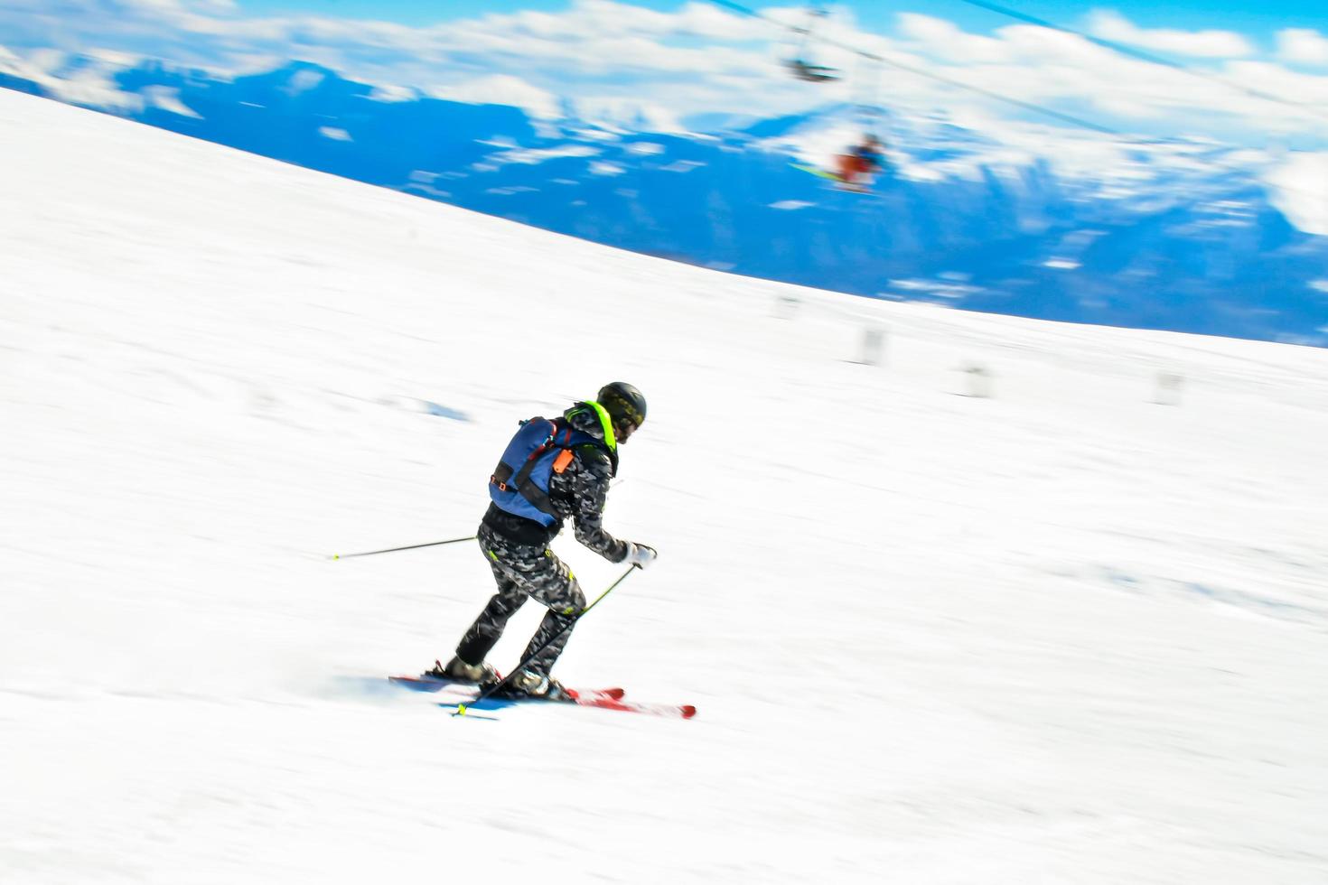 Dynamic picture of a skier on the piste in Alps. Woman skier in the soft snow. Active winter holidays, skiing downhill in sunny day. Intentional blur filter effect photo