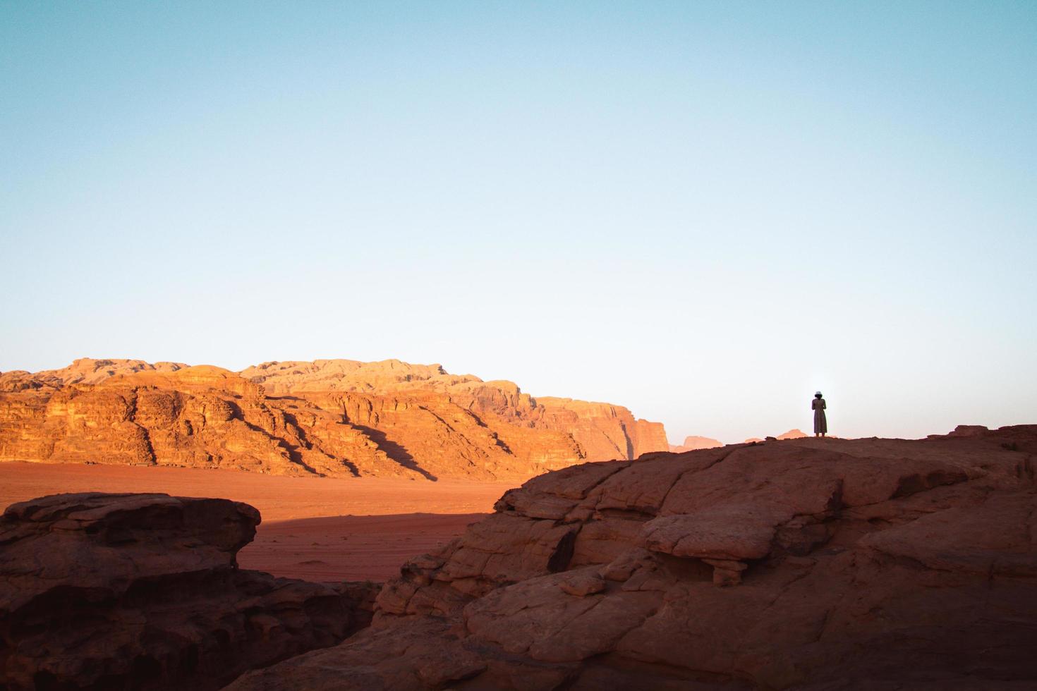 mujer turista parada en el acantilado en el mirador disfruta del panorama de wadi rum al amanecer. desierto de wadi rum - valle wadi saabit. Jordan explorar el concepto foto