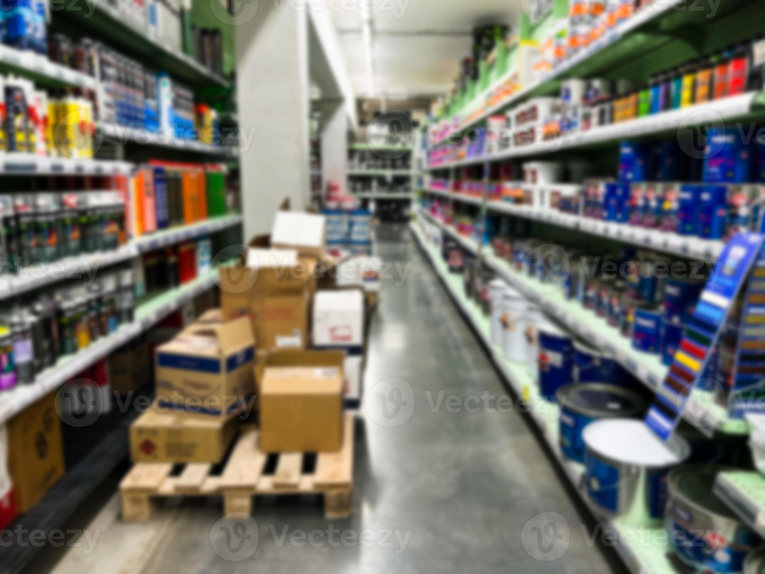 A blurry image of a hardware store with paints, varnish, brushes in a