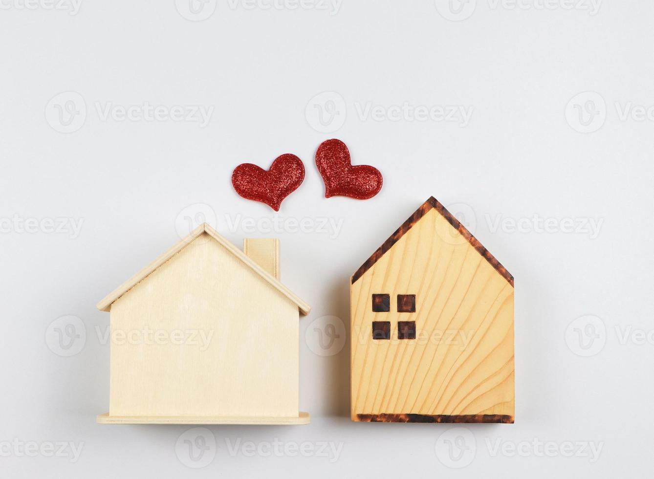 flat lay of two wooden model houses with red glitter hearts on white  background. dream house , home of love, strong relationship, neighboring houses, valentines. photo