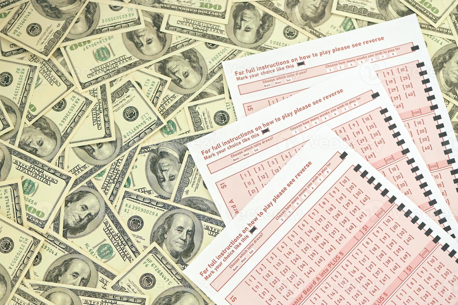 Pink gambling sheets with numbers for marking on big amount of hundred dollar bills. Lottery playing concept or gambling addiction. Close up photo