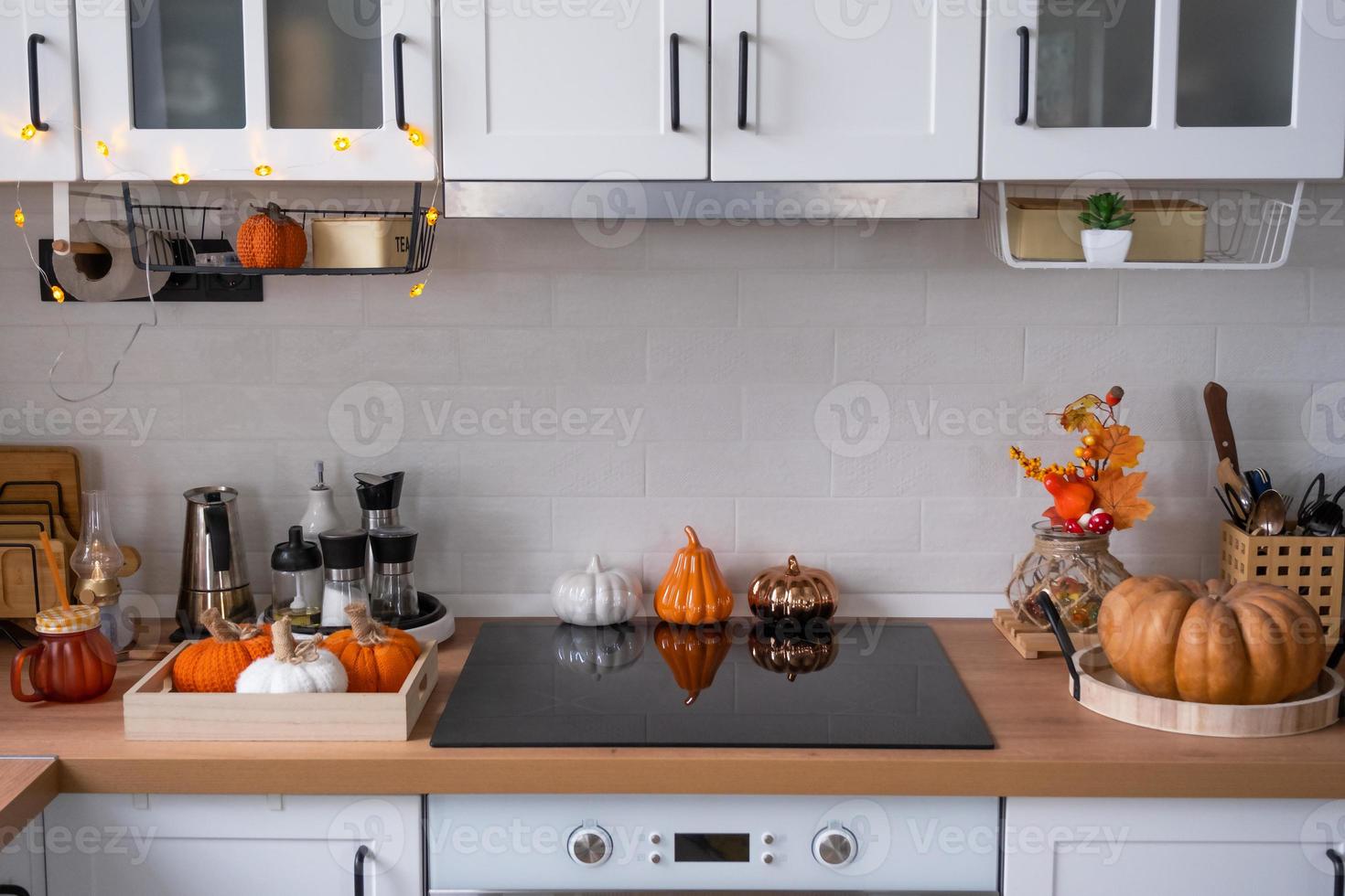 The interior of the Scandi-style white kitchen is decorated with pumpkins for Halloween. Autumn mood, home decor for the holiday photo
