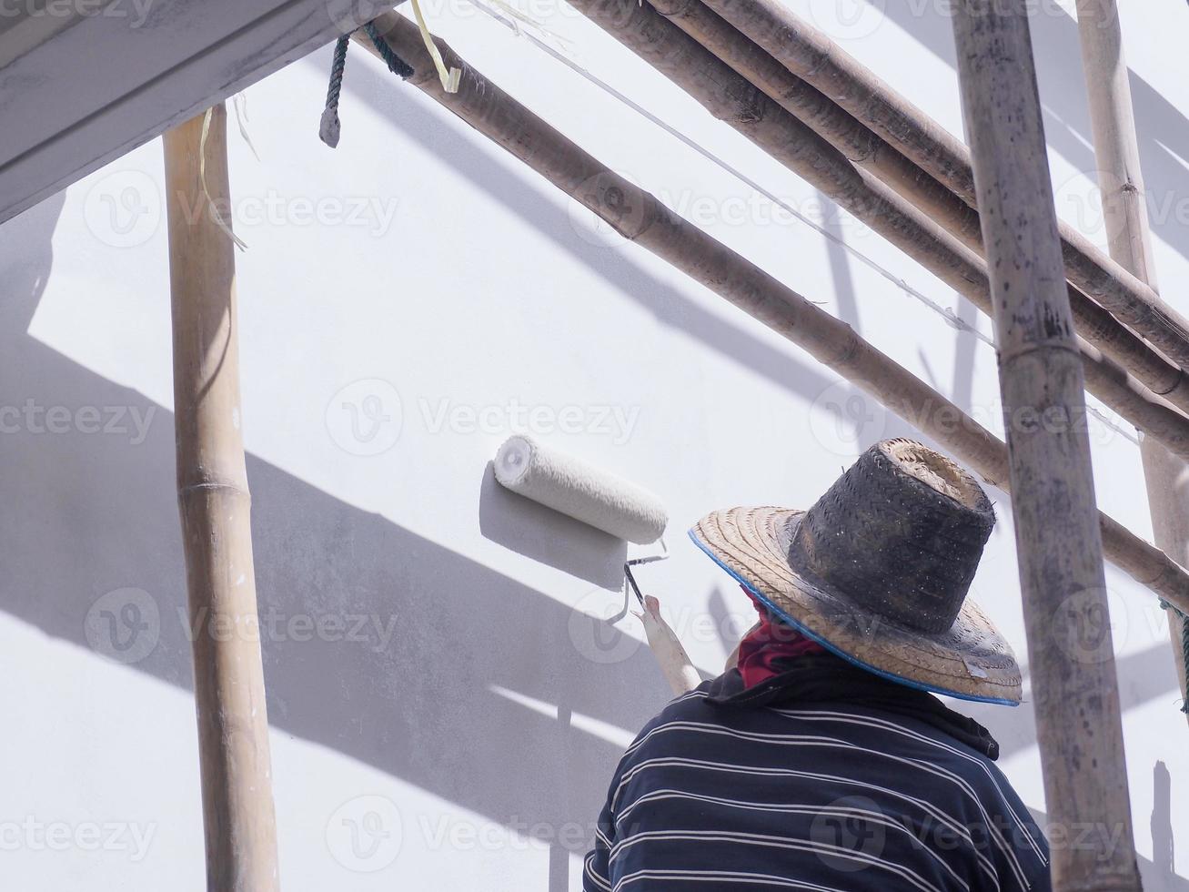 A worker is painting the walls of the house with a primer using a paint roller. photo