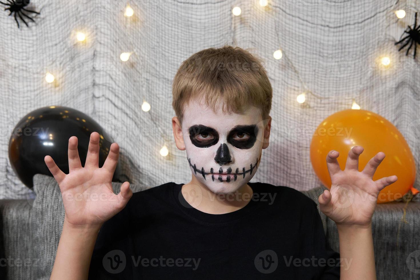 Portrait of a boy with makeup on his face in the form of skeleton for Halloween photo