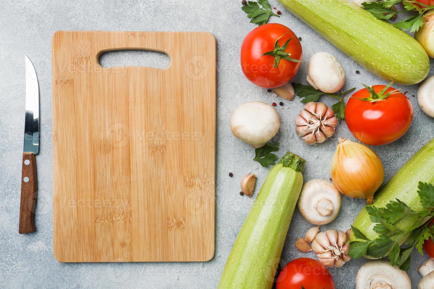 Set of different seasonal vegetables on a gray concrete background. Tomato zucchini onion garlic mushrooms parsley spices. Frame copy space. photo