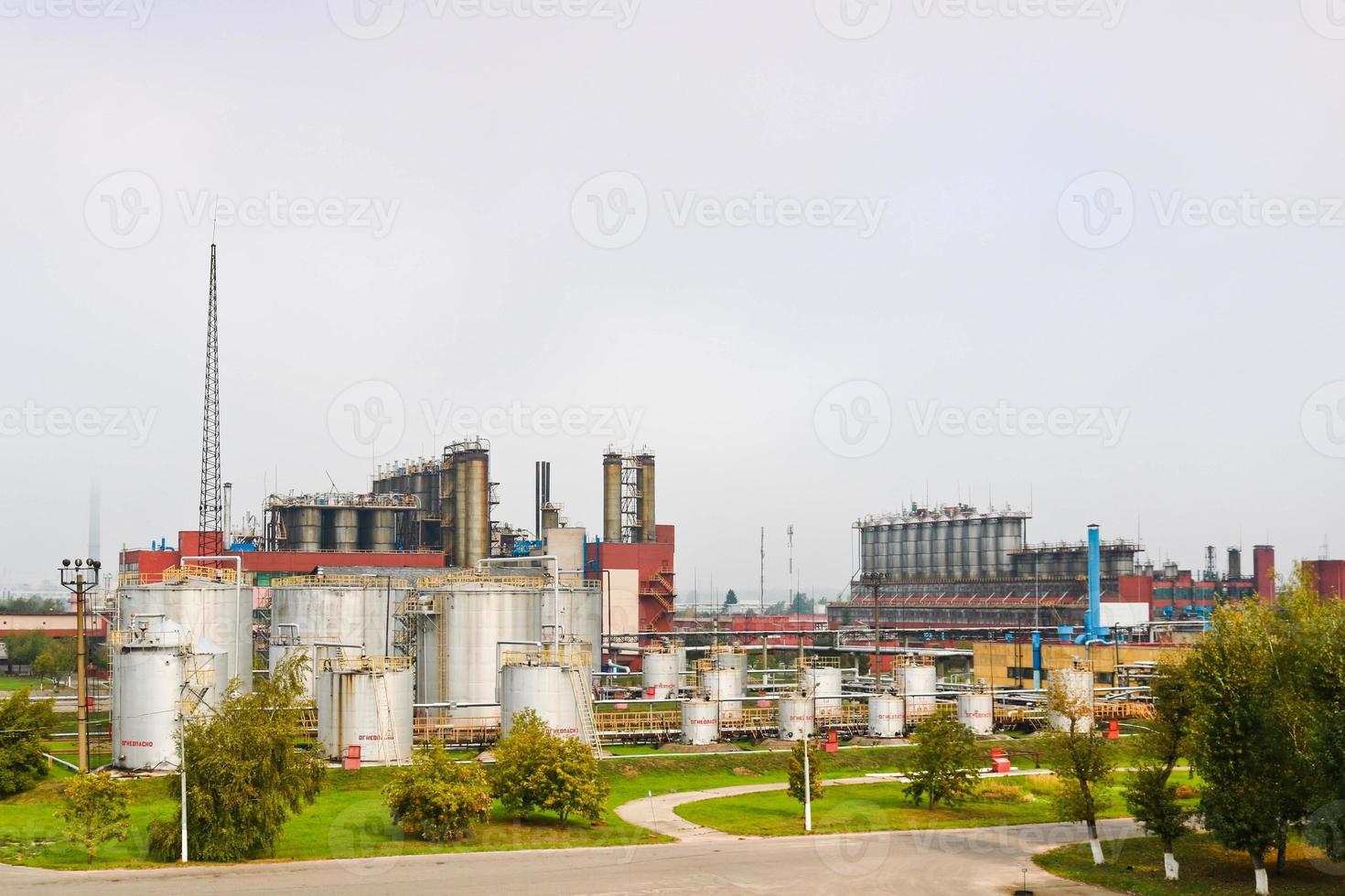 Industrial landscape, panoramic view of production. Chemical plants, columns, generators, pipes. Oil treatment systems. Buildings of production. Against the background of the cloudy sky and trees photo