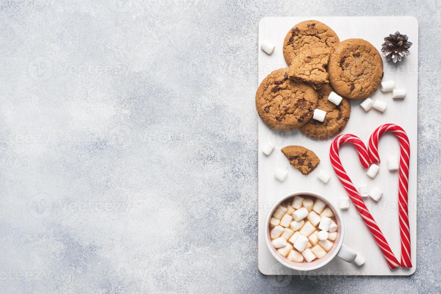 The chocolate chip cookie, Christmas cane caramel Cup cocoa and marshmallow cones Decorations on a gray background. Copy space Frame. photo