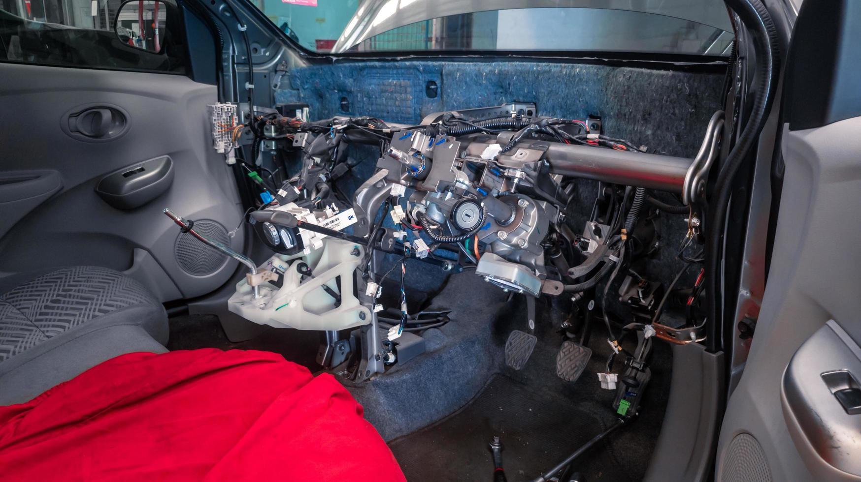 interior or dashboard of a car that is being disassembled or repaired, the steering column frame, shift lever, and interior cables are visible photo