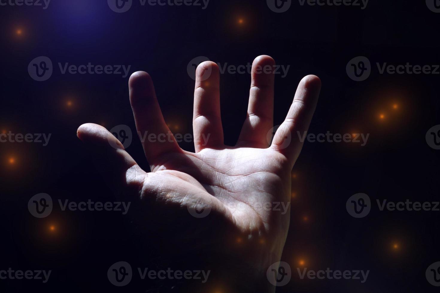 man hand up gesturing in the shadows, dark background photo