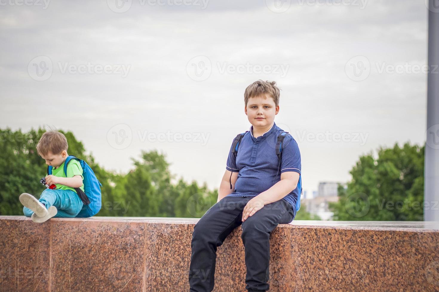 Portrait of a child, a boy against the backdrop of urban landscapes of skyscrapers and high-rise buildings in the open air. Children, Travel. Lifestyle in the city. Center, streets. photo