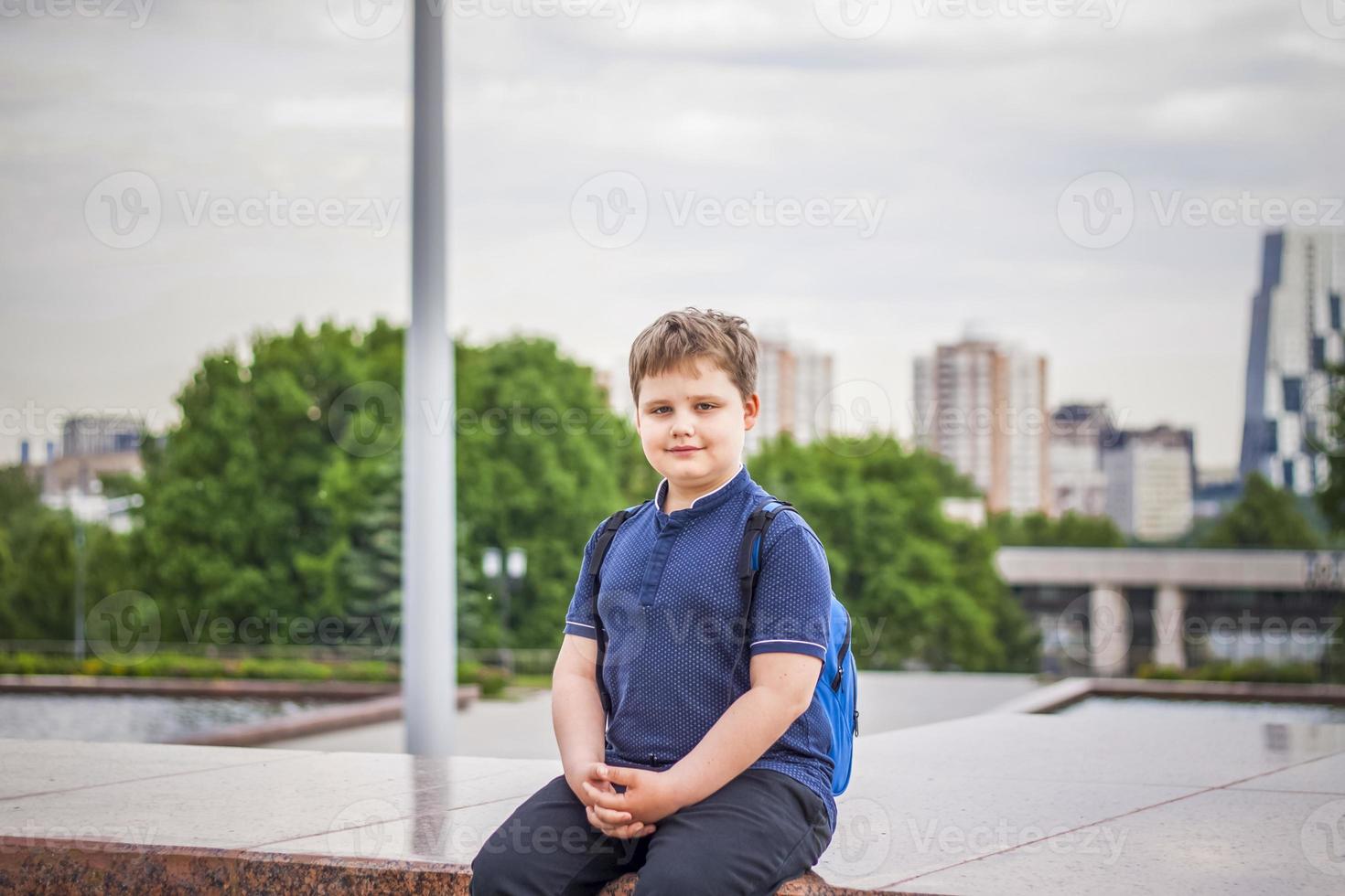 Portrait of a child, a boy against the backdrop of urban landscapes of skyscrapers and high-rise buildings in the open air. Children, Travel. Lifestyle in the city. Center, streets. photo