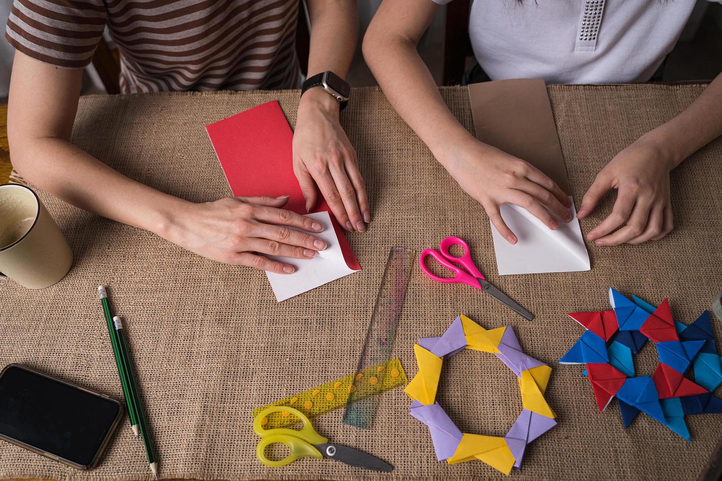 mom and daughter make origami from colored paper on self-isolation photo