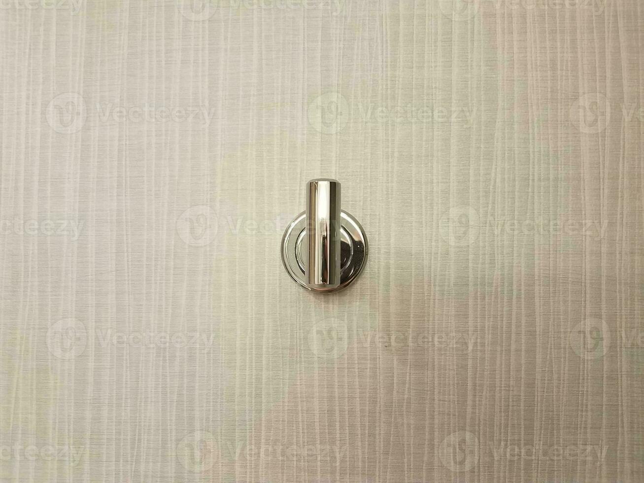 metalic metal coat hook or fixture on grey wall photo