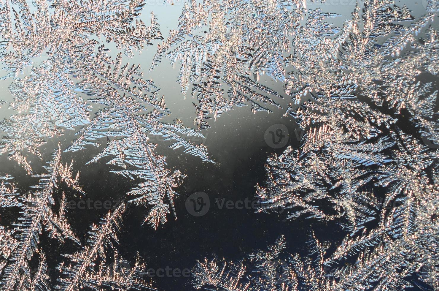 Snowflakes frost rime macro on window glass pane photo