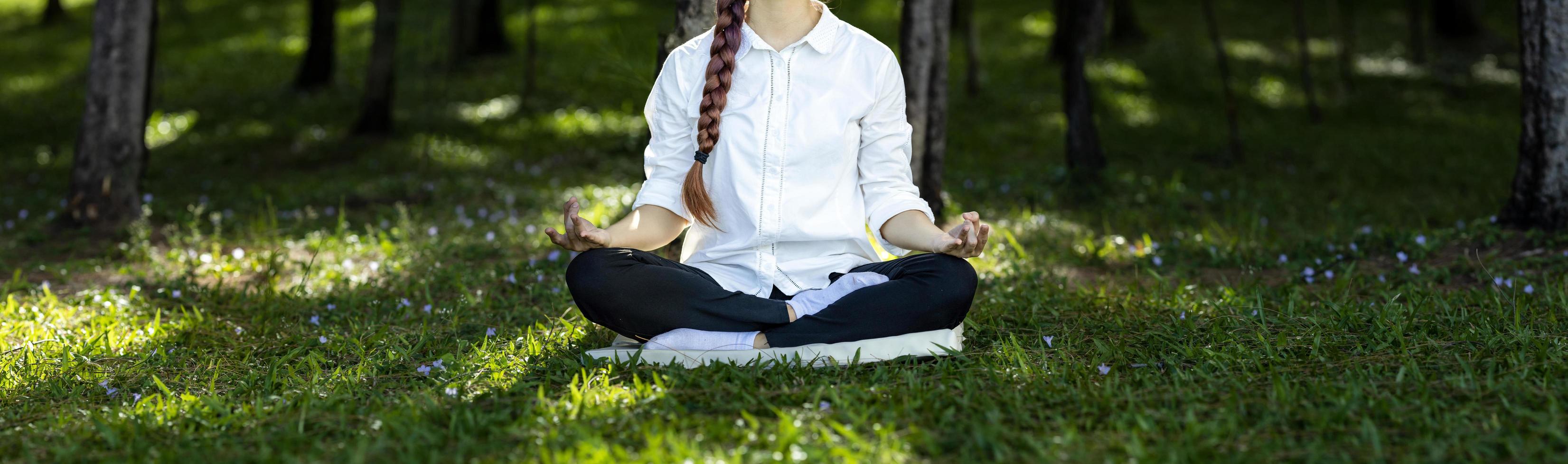 Panorama of woman relaxingly practicing meditation in the pine forest to attain happiness from inner peace wisdom for healthy mind and soul concept photo