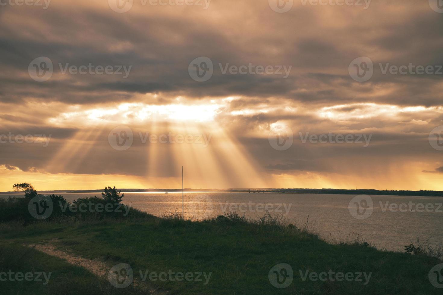 On the coast of Hundested. Sun rays break through the dramatic sky through the clouds photo