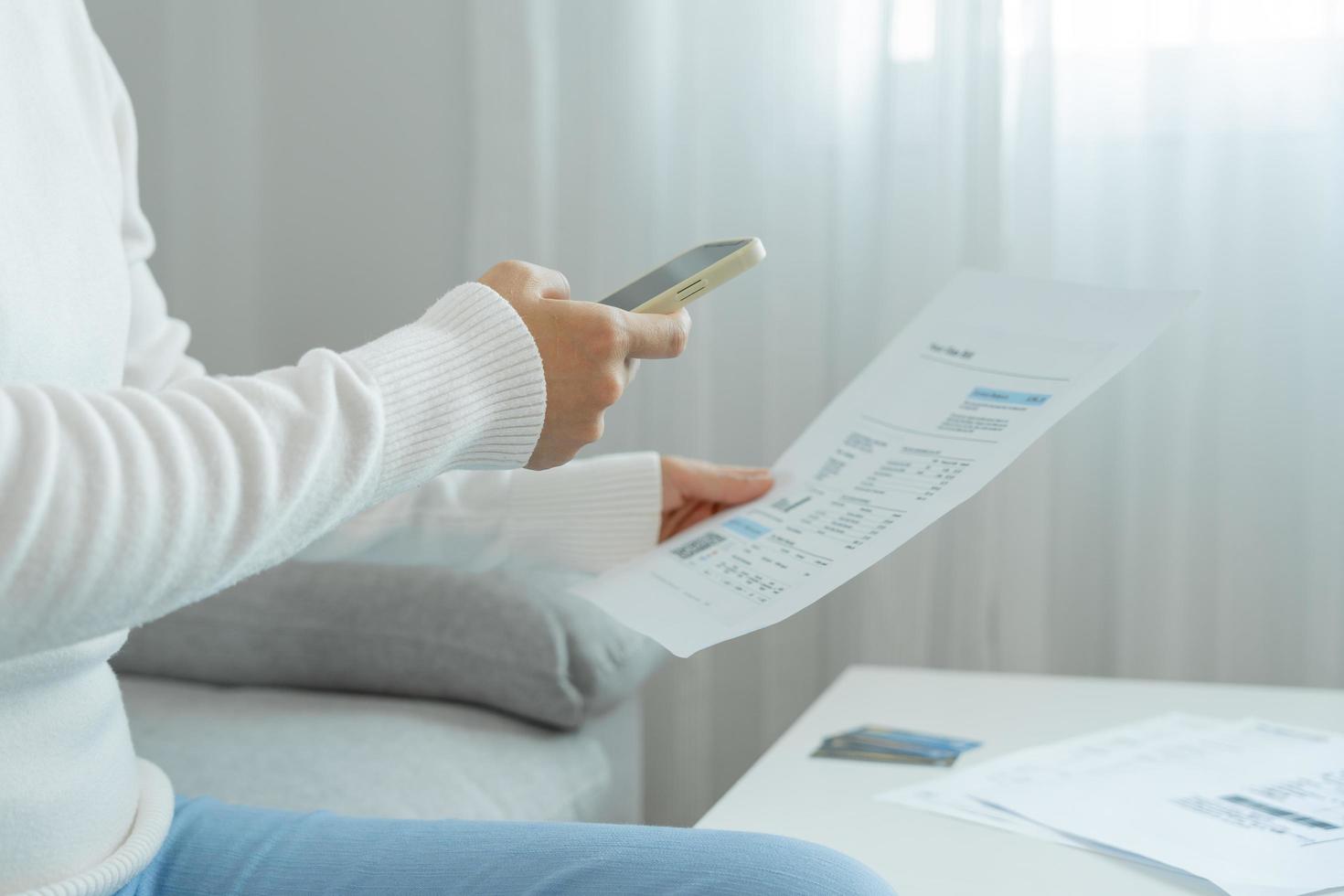 woman use phone to scan barcode or QR codes to pay credit card bill after receiving document invoice online. payment, receive, paying electricity, digital payments without money, technology, scanning photo