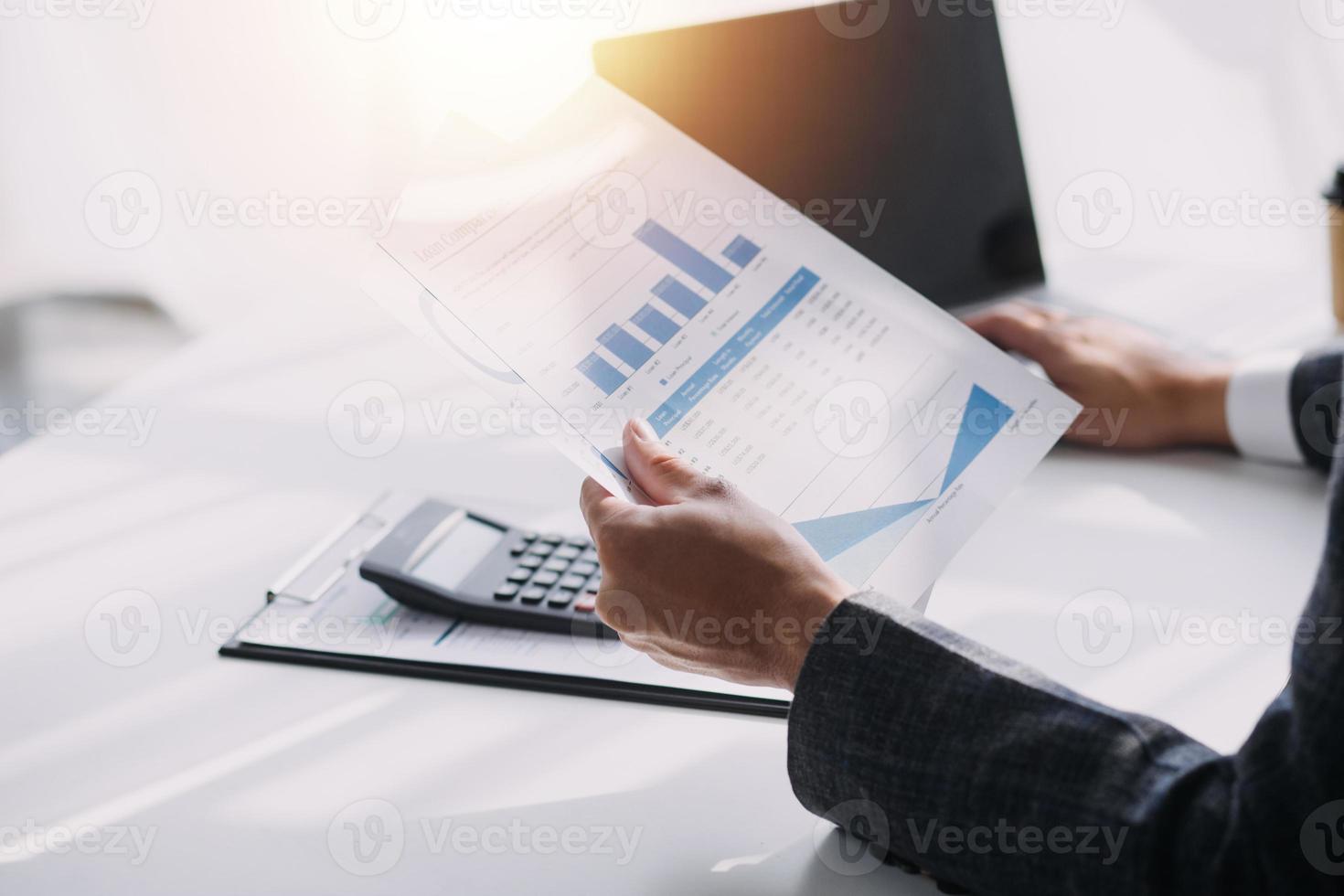 Asian Business woman using calculator and laptop for doing math finance on an office desk, tax, report, accounting, statistics, and analytical research concept photo