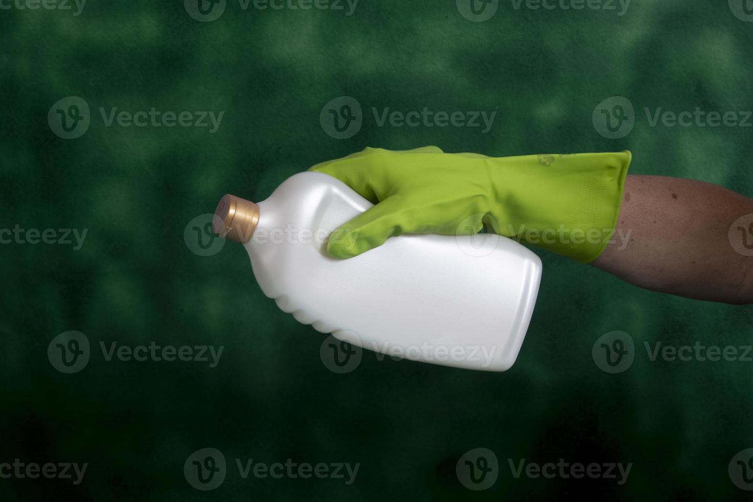 hand with protective glove holding packaging of cleaning products used for home hygiene photo