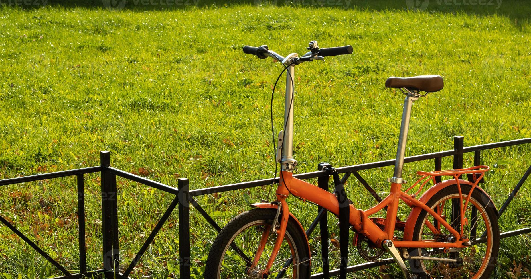 Walking compact city bike on green grass background with copy space. City tourism and bike rental service photo