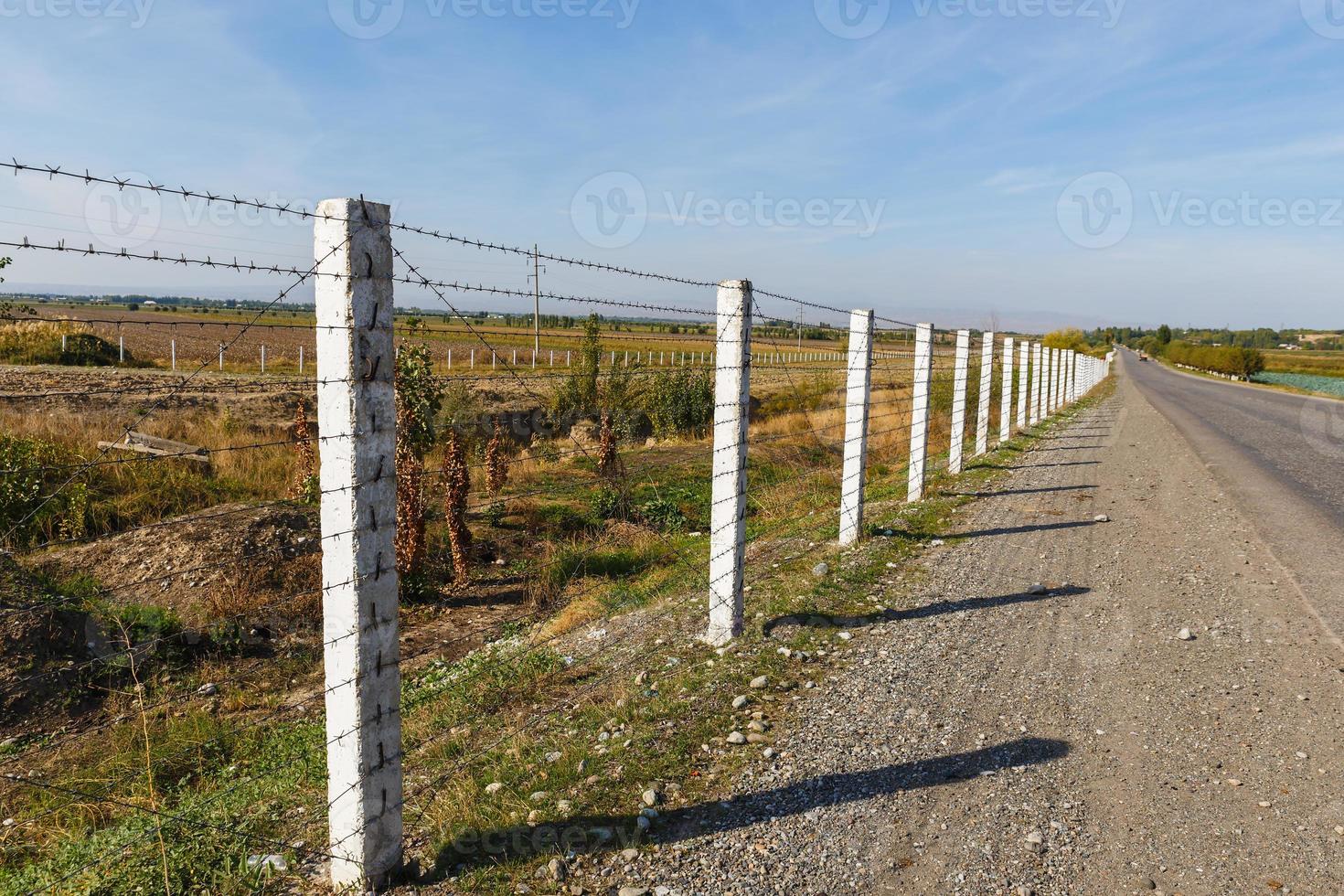 barbed wire fence along the road, state border between Kyrgyzstan and Uzbekistan photo