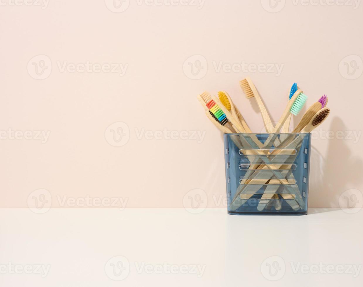 wooden toothbrushes in a plastic cup on a white table. Beige background, zero waste photo