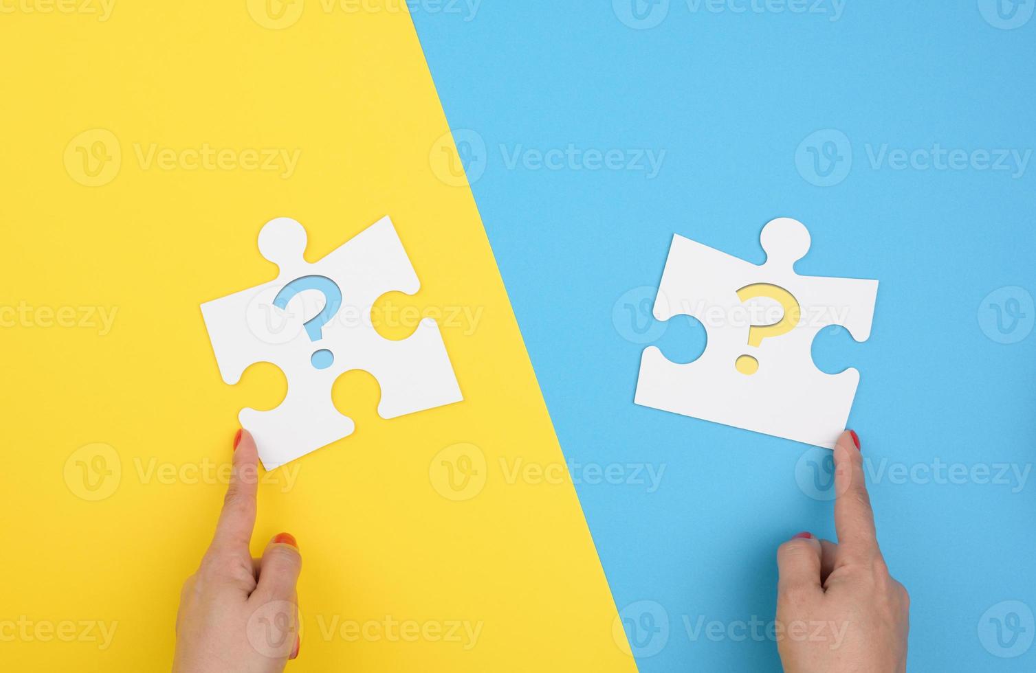 female hand holds a fragment of a white large puzzle on a yellow blue background, concept of finding an idea photo