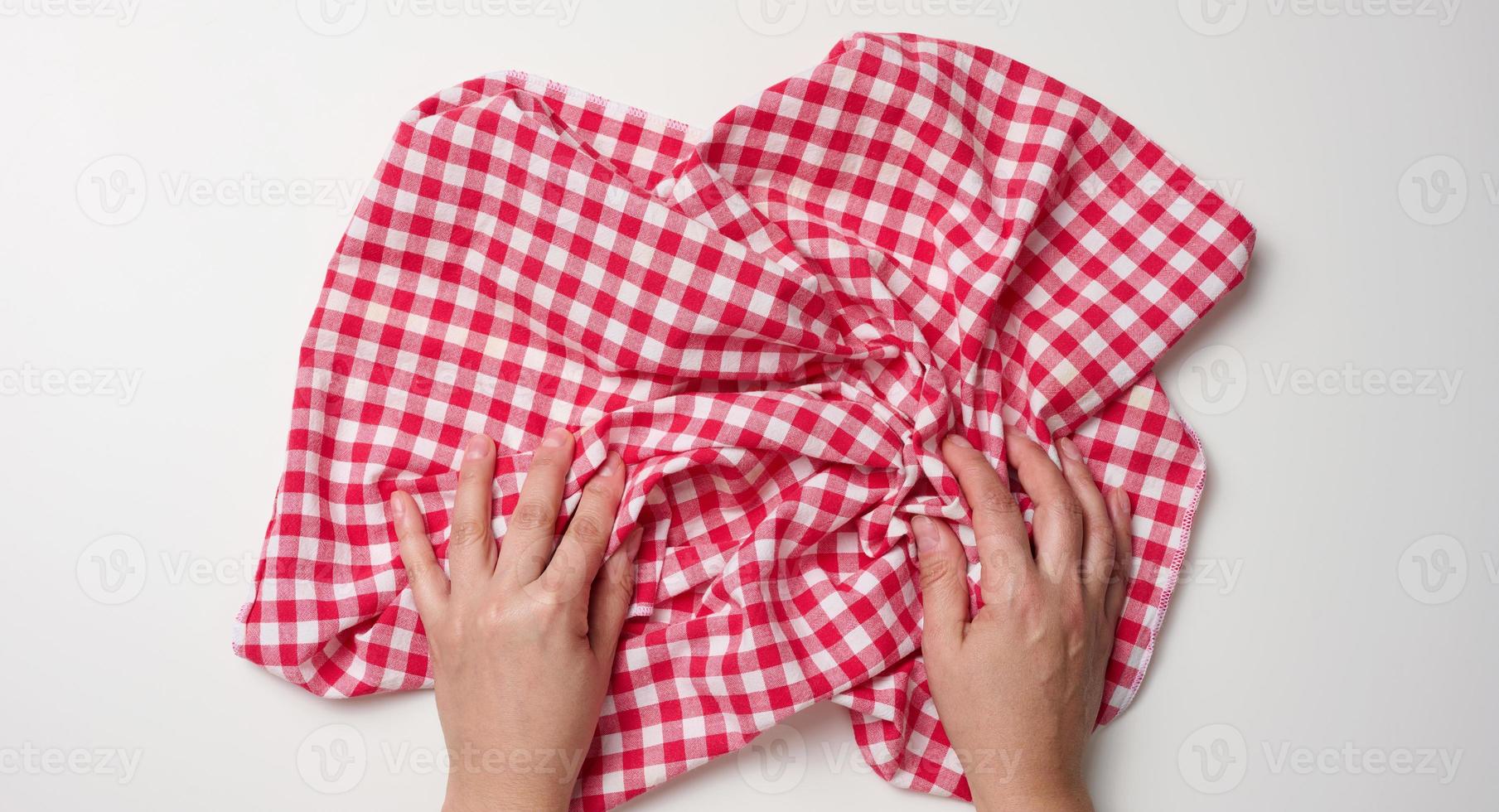 two female hands holding a red kitchen napkin on a white table, top view photo