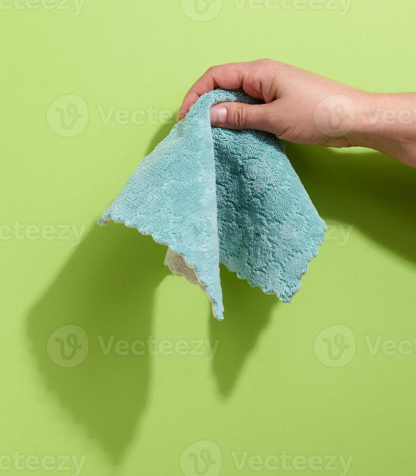 female hand holding a bluew rag on a green background photo