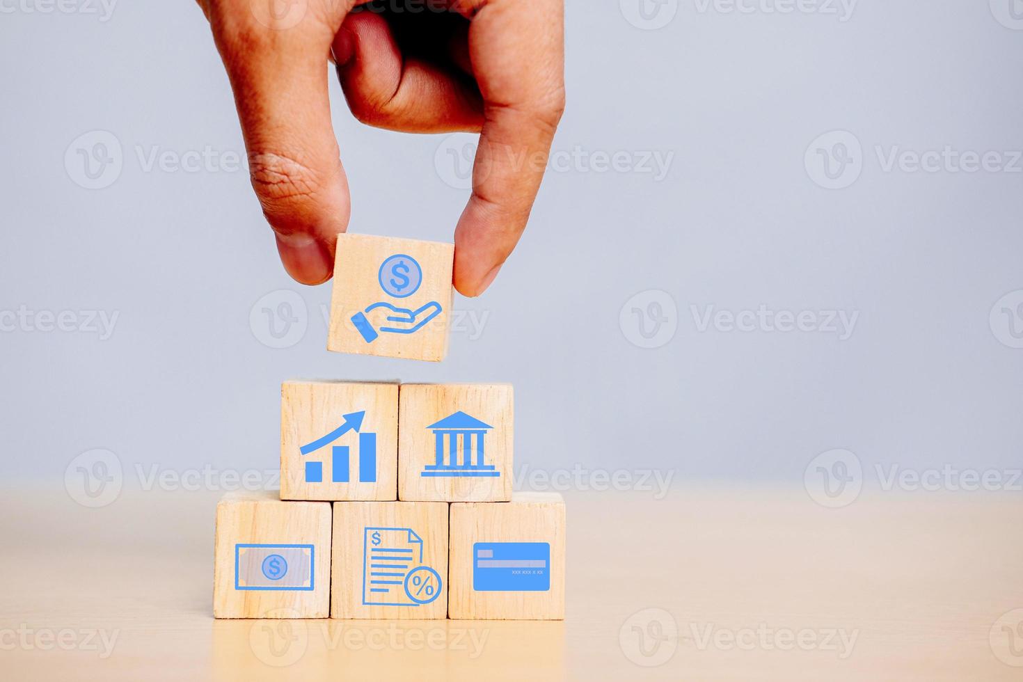 Hand holding a wooden block with finance icons Bank loan to invest in assets, Loan of concept. photo