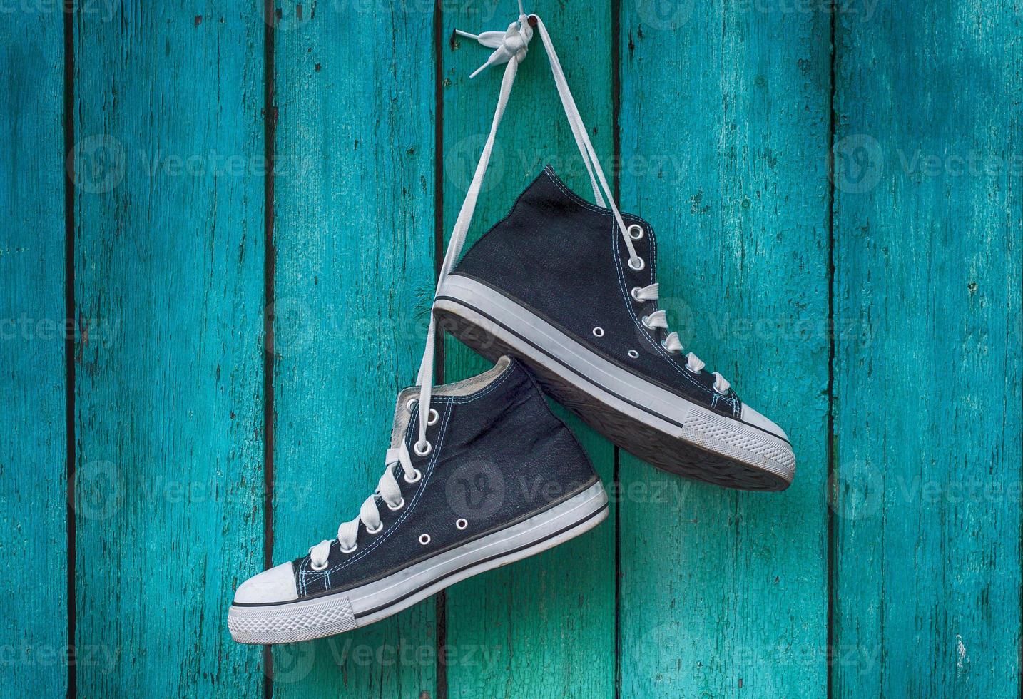 pair of blue men's sports sneakers hanging from a nail on the wall of the old shabby green photo