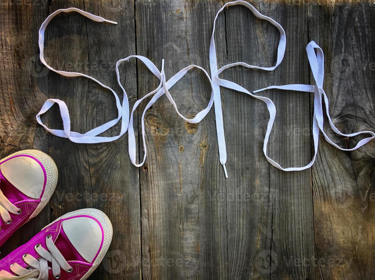 Purple sneakers and lace on shabby old wooden surface photo