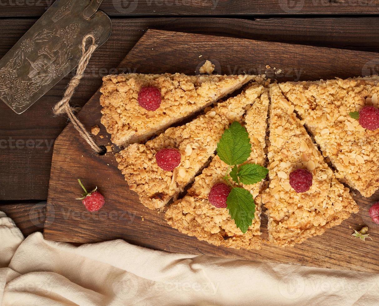 sliced triangular pieces of crumble pie with apples on a brown wooden board photo