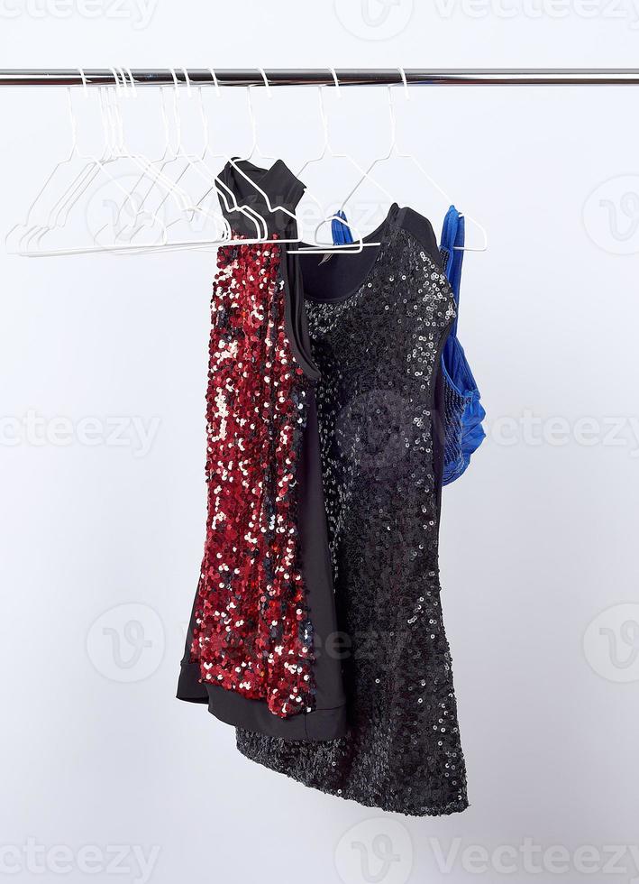 black women's blouses  with red and black sequins hanging on a white iron hanger photo