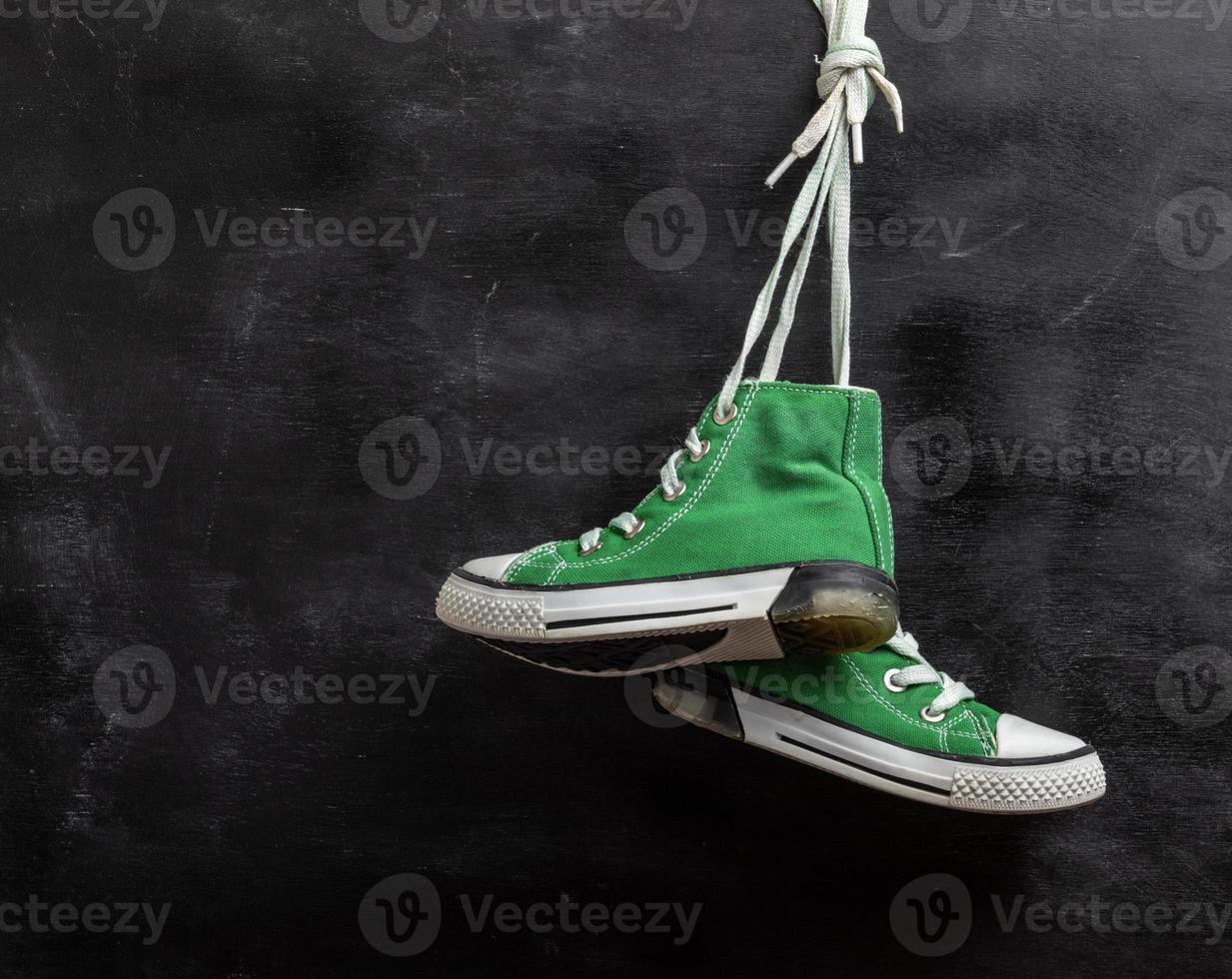 pair of worn green textile sneakers hang photo