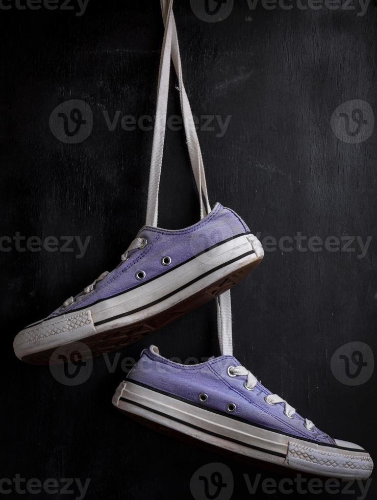 purple textile sneakers hanging on a lace photo