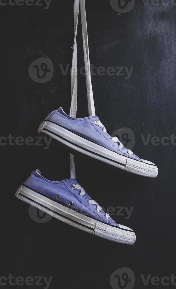 pair of purple textile sneakers hanging on a lace photo