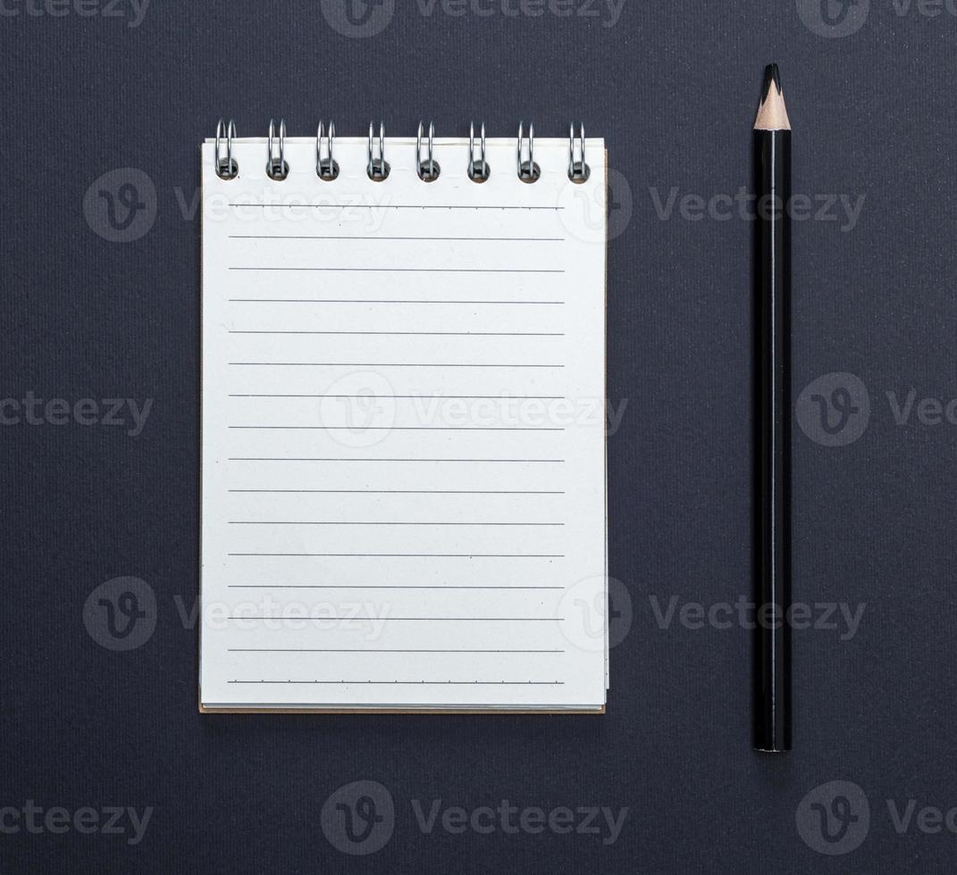 notebook with white sheets in line and black wooden pencil photo