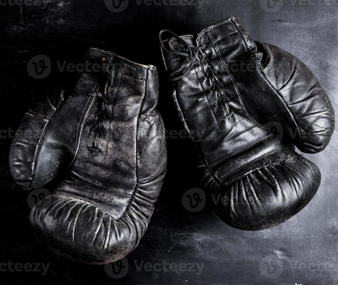 pair of old leather boxing gloves with laces on a wooden background photo