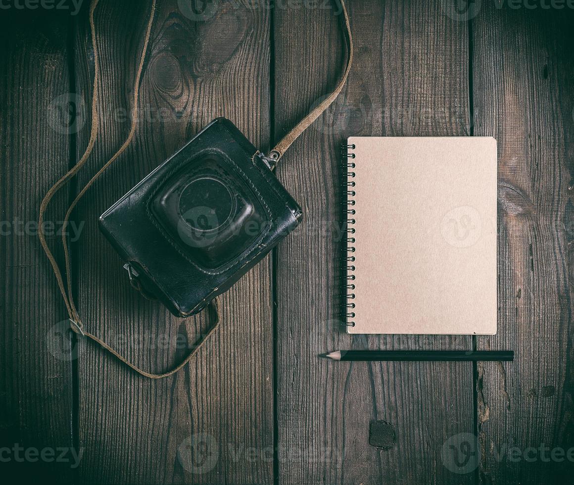 old vintage camera in a leather case and a notepad with a wooden black pencil photo