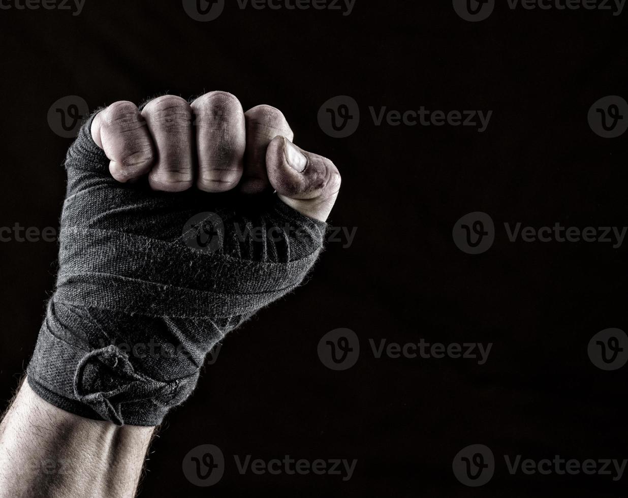 lifted up fist of athlete wrapped in black textile bandage photo