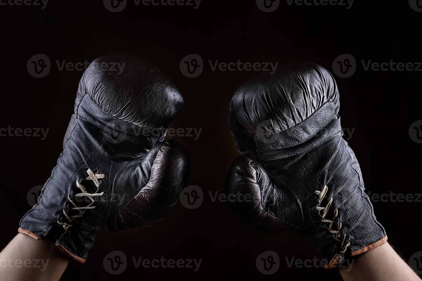 raised up arms of an athlete dressed in leather brown boxing gloves photo