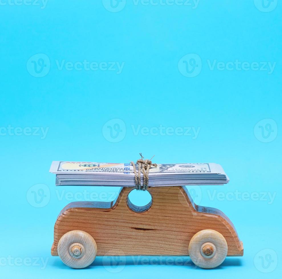 wooden children's car carries on the top of the roof a stack of paper banknotes photo