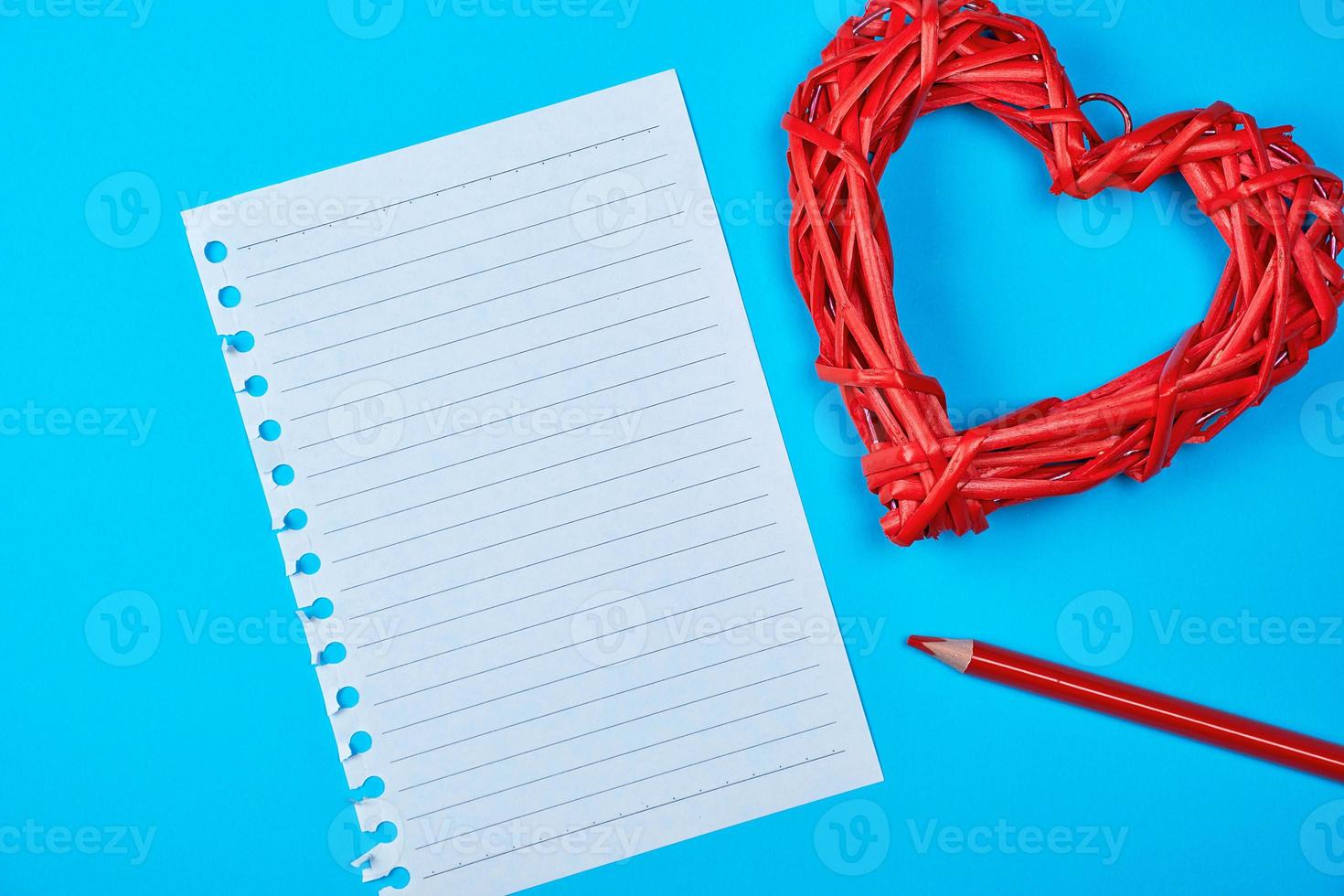 wooden wicker red heart and an empty white sheet of notepad photo