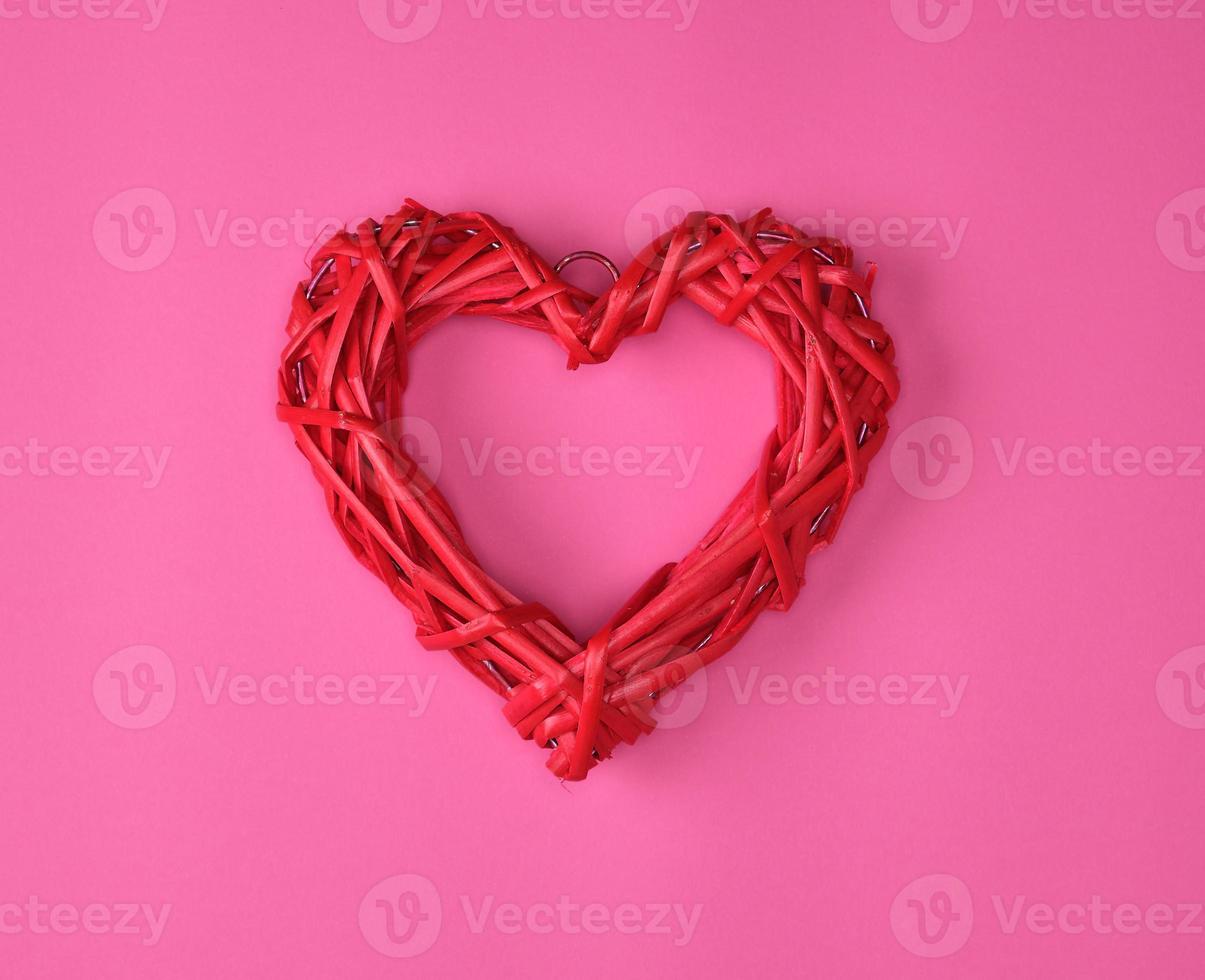 one wicker red heart on a pink background photo