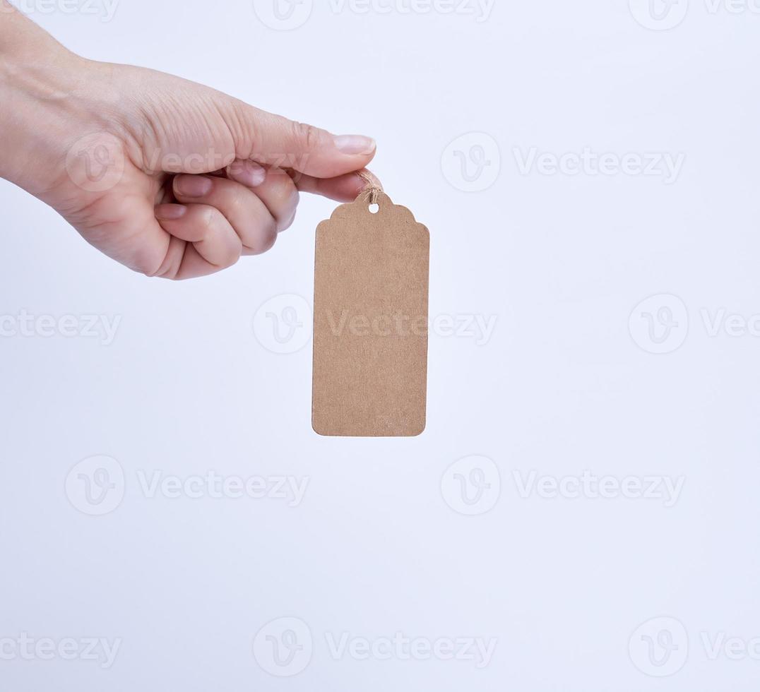 female hand holding a paper brown blank tag photo
